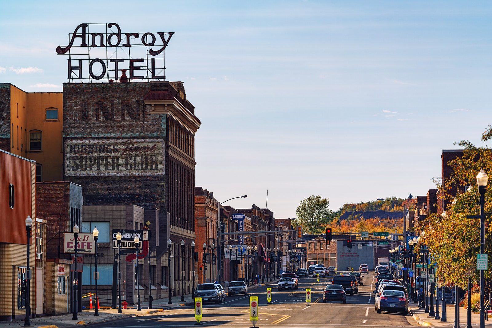 Downtown Hibbing in fall, with the Androy Hotel sign and autumn color on the hills beyond.